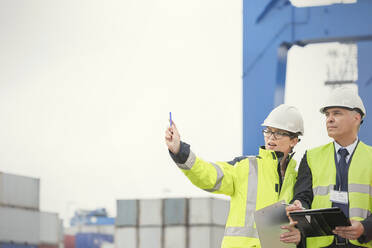 Dockarbeiter und Manager mit Klemmbrett im Gespräch auf einer Werft - CAIF25104