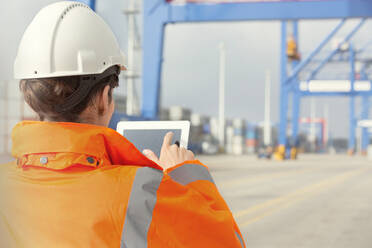 Weiblicher Hafenarbeiter mit digitalem Tablet in einer Werft - CAIF25108