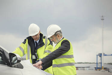 Dockarbeiter und Manager bei der Überprüfung eines Bauplans in einer Werft - CAIF25115
