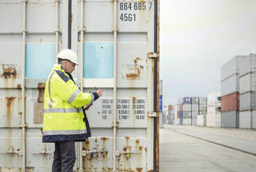 Hafenarbeiter bei der Kontrolle von Frachtcontainern in einer Werft - CAIF25118