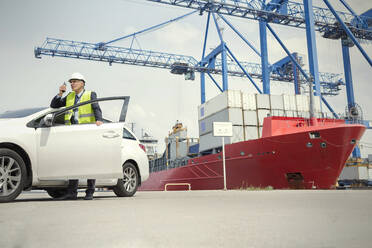 Dock-Manager mit Walkie-Talkie vor dem Auto in der Werft - CAIF25126