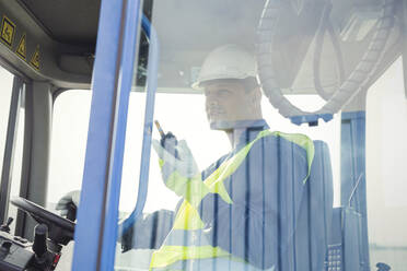 Hafenarbeiter mit Walkie-Talkie bei der Bedienung eines Gabelstaplers - CAIF25129