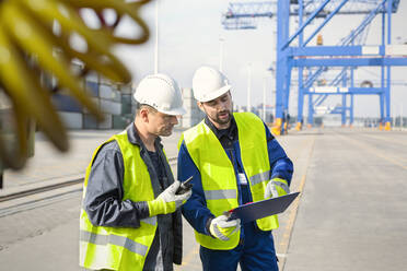 Dockarbeiter mit Walkie-Talkie und Klemmbrett treffen sich in der Werft - CAIF25130