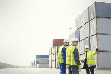 Dockarbeiter und Manager im Gespräch an Frachtcontainern auf einer Werft - CAIF25132