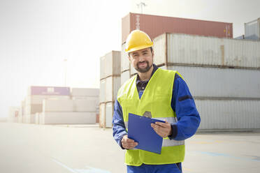 Porträt eines selbstbewussten Hafenarbeiters mit Klemmbrett in einer Werft - CAIF25134