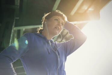 Young female runner with headphones resting - CAIF25139