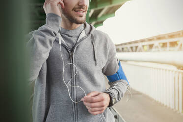 Male runner listening to music with headphones and mp3 player - CAIF25155