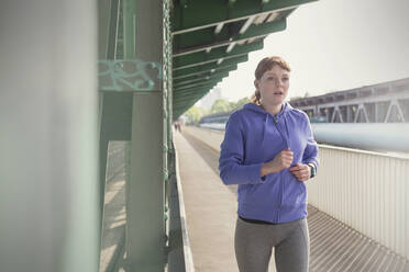 Engagierte junge Frau läuft auf dem sonnigen Bahnsteig - CAIF25160