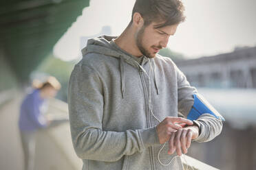 Young male runner checking smart watch - CAIF25167