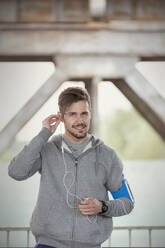 Portrait confident young male runner with headphones and mp3 player arm band - CAIF25178