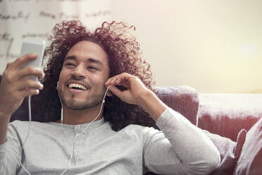Smiling young man listening to music with headphones and mp3 player - CAIF25192