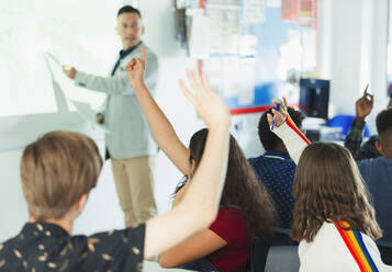 High school students with hands raised during lesson in classroom - CAIF25227