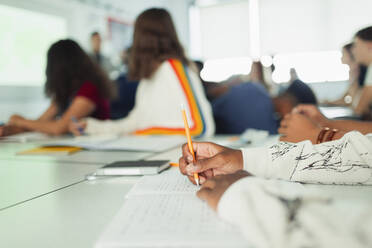 Gymnasiastin beim Lernen und Schreiben in einem Notizbuch während des Unterrichts im Klassenzimmer - CAIF25235