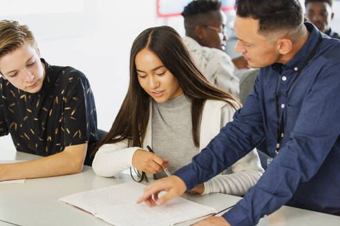 Gymnasiallehrer hilft Schülern bei den Hausaufgaben im Klassenzimmer - CAIF25236