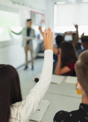 High school girl student raising hand, asking question during lesson in classroom - CAIF25237