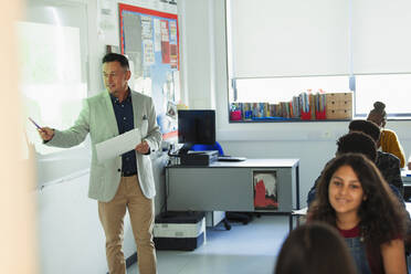 Männlicher High-School-Lehrer, der vor einer Projektionsfläche im Klassenzimmer Unterricht erteilt - CAIF25254
