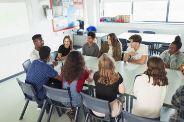 High school students talking in debate class at table in classroom - CAIF25255