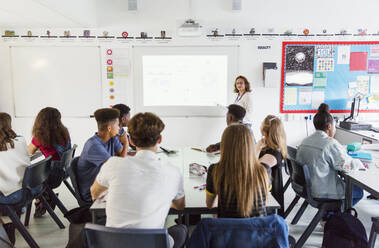 Gymnasiasten beobachten eine Lehrerin, die eine Unterrichtsstunde auf einer Projektionsfläche im Klassenzimmer leitet - CAIF25263