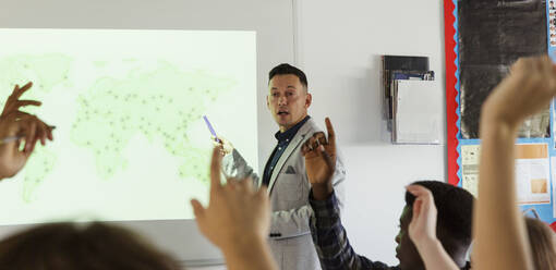 Male high school teacher leading lesson at projection screen in classroom - CAIF25270