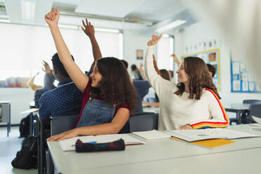 Gymnasiastinnen mit erhobenen Händen während des Unterrichts im Klassenzimmer - CAIF25272