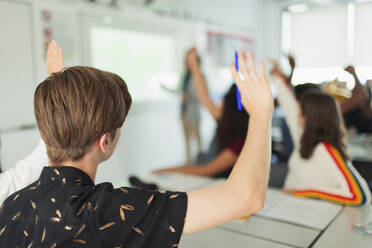 High school boy student with hand raised during lesson in classroom - CAIF25281