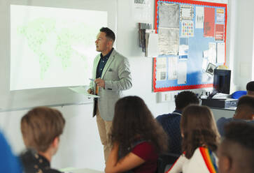 Gymnasiallehrer, der eine Geografiestunde an der Projektionsfläche im Klassenzimmer leitet - CAIF25290