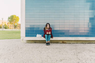 Teenage girl reading book outdoors - ERRF02963