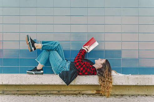 Teenage girl reading book outdoors - ERRF02964