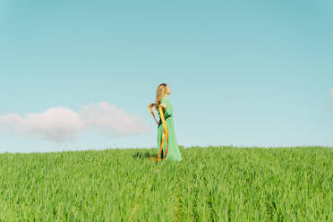 Junge Frau in grünem Kleid auf einem Feld mit einer Schleife - ERRF02974
