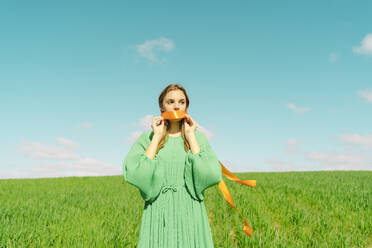 Junge Frau in grünem Kleid auf einem Feld mit einer Schleife - ERRF03004