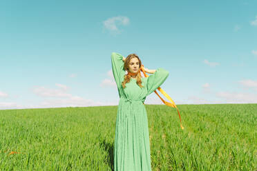 Junge Frau in grünem Kleid auf einem Feld mit einem Band um den Hals - ERRF03006