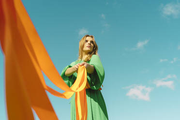Young woman wearing a green dress holding orange ribbons - ERRF03020