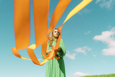 Junge Frau in grünem Kleid mit orangefarbenen Bändern - ERRF03021