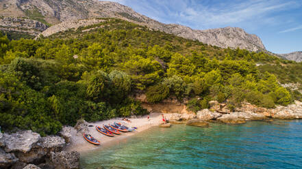 Luftaufnahme einer Gruppe von Kajakfahrern, die sich an einem abgelegenen Strand bei Drvenik in Dalmatien, Kroatien, ausruhen. - AAEF07837