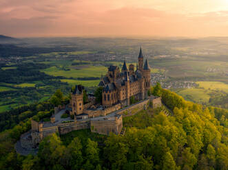 Aerial view of Hechingen, Baden-Württemberg, Germany with mount Hohenzollern, Hohenzollern Castle and trees during sunset - AAEF07897