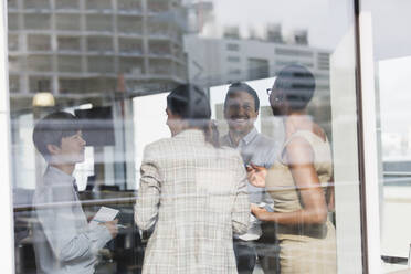 Lächelnde Geschäftsleute im Gespräch am sonnigen Bürofenster - CAIF25354