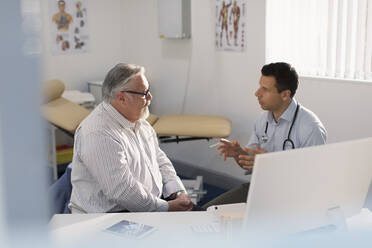 Männlicher Arzt im Gespräch mit einem Patienten in einer Arztpraxis - CAIF25367