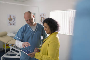 Doctors with digital tablet meeting in examination room - CAIF25377