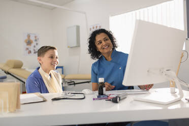 Weibliche Kinderärztin und Junge Patient im Gespräch, mit Computer in der Arztpraxis - CAIF25385