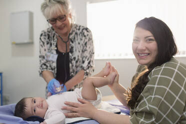 Portrait glückliche Mutter mit kleiner Tochter und Kinderarzt im Untersuchungsraum - CAIF25393