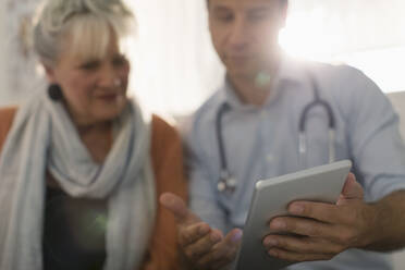Männlicher Arzt zeigt einem Patienten ein digitales Tablet - CAIF25410