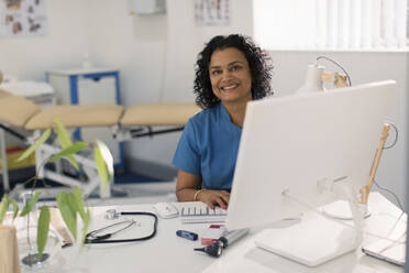 Porträt einer selbstbewussten Ärztin bei der Arbeit am Computer in einer Arztpraxis - CAIF25427