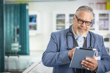 Männlicher Arzt mit digitalem Tablet in der Klinik - CAIF25449