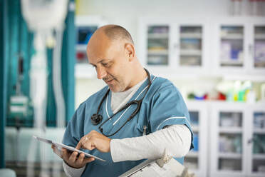Männlicher Arzt mit digitalem Tablet im Krankenhaus - CAIF25450