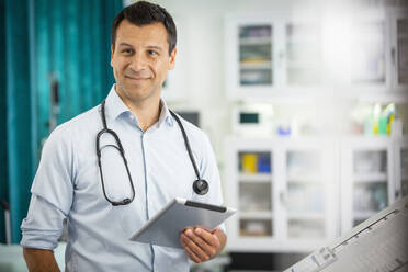 Porträt selbstbewusster männlicher Arzt mit digitalem Tablet im Krankenhaus - CAIF25468