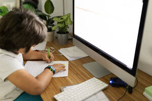 Boy sitting at desk at home painting schedule - VABF02686