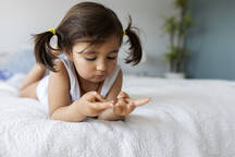 Portrait of little girl in underwear lying on bed at home stock photo