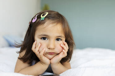 Porträt eines gelangweilten kleinen Mädchens auf dem Bett liegend - VABF02727