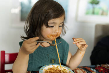 Portrait of little girl with smeared face eating pasta - VABF02729