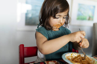 Portrait of little girl with smeared face eating pasta - VABF02730